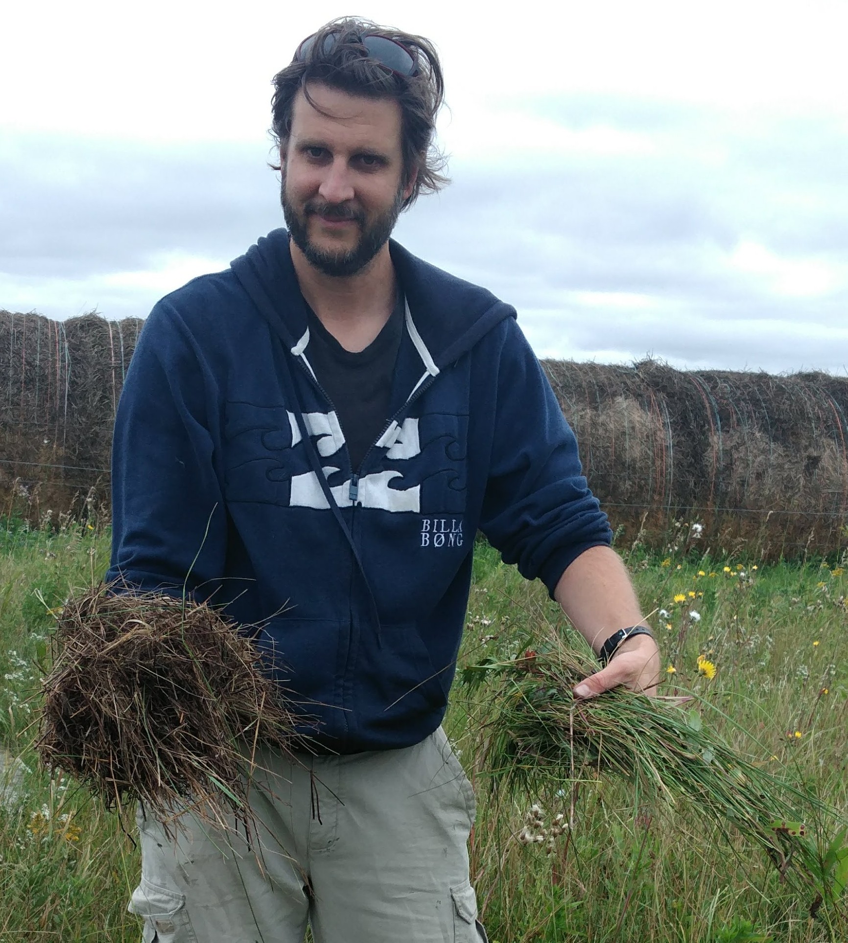 Alex smiling and holding a handful of forage/grass out to the viewer